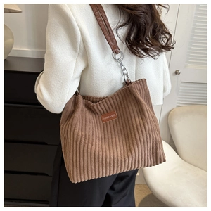Close-up of brown corduroy tote bag with leather strap and metal chain detail