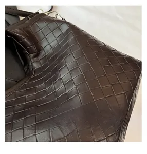 Close-up of deep brown intrecciato woven leather showing texture and fine stitching detail