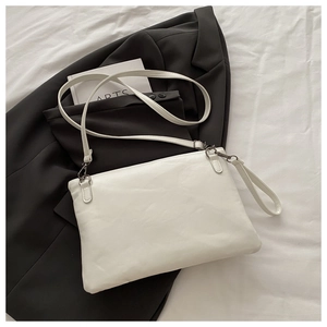 Minimalistische weiße Crossbody-Umschlagtasche über einem schwarzen Blazer für urbanen Stil