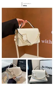 Detailed view of white crossbody bag with golden chain and square buckle hardware