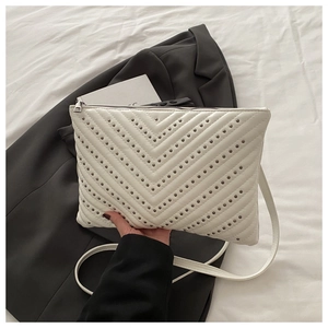 Detail der weißen gesteppten Ledertasche mit dunkelgrauen Nieten und Silberreißverschluss