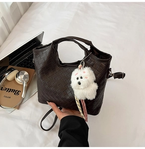 Detailed woven texture of dark brown leather bucket bag with cute plush puppy charm