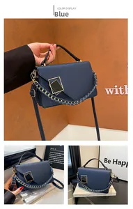 Detail of blue crossbody bag featuring a golden geometric clasp and chain strap accent