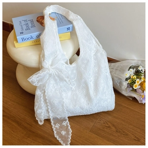 Detail of white lace tote bag with floral embroidery and elegant bow ribbon accessory