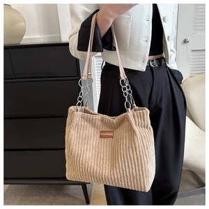 Detail of khaki corduroy tote bag showing vertical texture and silver metal chain strap