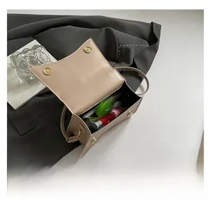 Top view of beige leather crossbody bag open to show storage for phone and lipstick