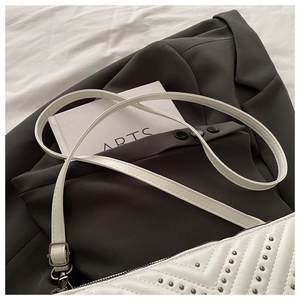 Detail der weißen gesteppten Handtasche mit silbernen Nieten auf minimalistischem Hintergrund
