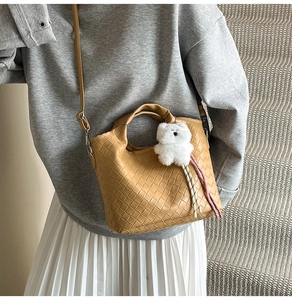 Detail of camel woven leather crossbody bag with cute bear charm and tassel on handle