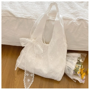 Detailed embroidery on white lace tote bag with large decorative side bow detail