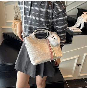 Detail of cream woven bucket bag with plush charm and braided strap for daily wear