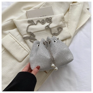 Detail of silver rhinestone bucket bag with pearl drawstring and metal chain strap