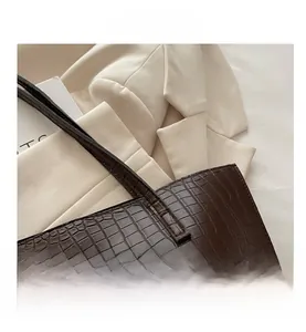 Detailed view of dark brown crocodile pattern leather tote bag with neat stitching