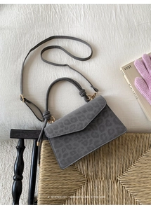 Detail der grauen Handtasche mit Leopardenmuster, Goldbeschlägen und Wildlederoptik