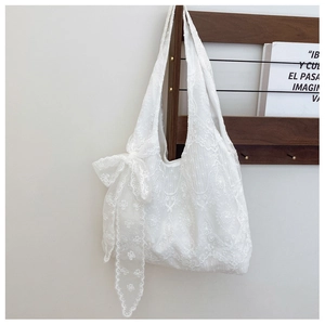 Detail of white lace floral embroidery on tote bag with a matching side bow decoration