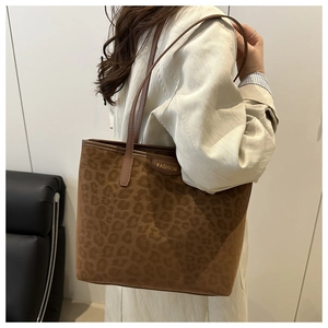 Close-up of leopard print suede tote bag with gold metal fashion badge and shoulder straps