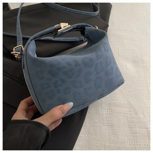 Détail du sac à main bleu avec imprimé léopard, fini daim et fermoir en métal doré brillant