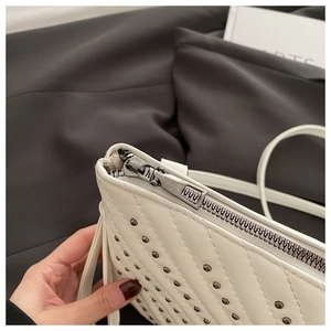 Detail der weißen gesteppten Kunstledertasche mit Silbernieten und Reißverschluss