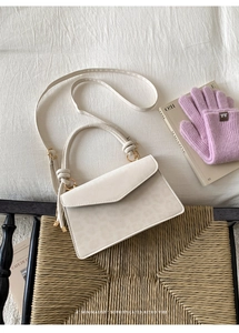 Close-up of cream square bag with leopard embossing, knot handle, and adjustable strap