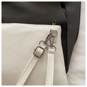 Makroaufnahme von verstellbarem Riemenhaken und Hardware an weißer Achseltasche