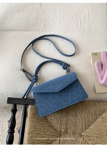 Detail of blue leopard print crossbody bag with gold hardware and envelope flap design