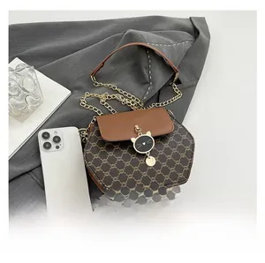 Détail du sac hexagonal en toile marron avec chaîne et pendentif chat