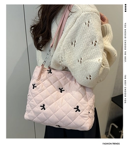 Pink quilted puffer tote bag detail with black bow embroidery and leather shoulder strap