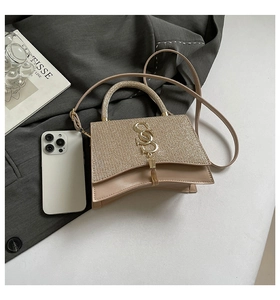 Detail of champagne gold sequin handbag with S-logo metal charm and curved base