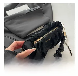 Détail d'un sac plissé noir avec fermeture éclair dorée et bandoulière chaîne