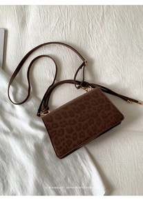Top view of retro dark brown leopard print handbag with golden hardware on white fabric
