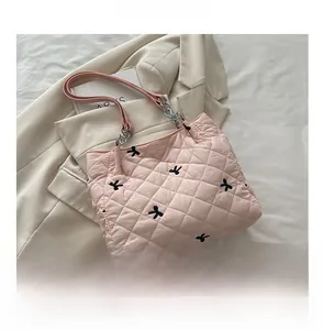 Detail of pink quilted tote bag with black bow embroidery and metal chain strap