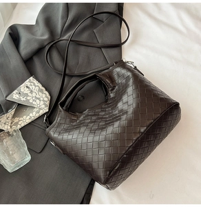Detailed view of dark brown woven leather texture and shoulder strap of the bucket bag