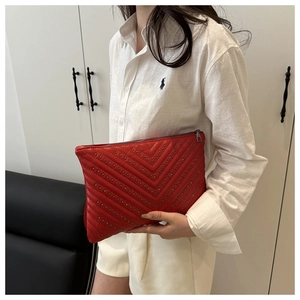 Detail der roten gesteppten Clutch-Tasche mit silbernen Metallnieten und Reißverschluss