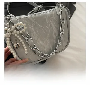 Détail du sac gris à texture marbrée avec chaîne argentée et pendentif coeur