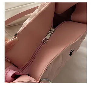 Detailed close-up of the smooth metal zipper and quilted fabric on the pink tote bag