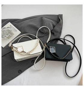 Close-up of stylish rectangle crossbody bags with metal buckle and woven chain detail