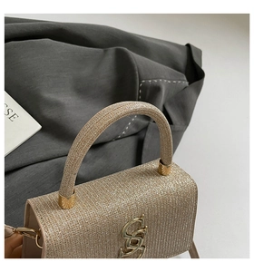 Macro shot of shimmering gold glitter texture and S-shaped metal buckle on small handbag