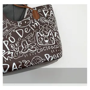 Dettaglio della borsa tote marrone scuro con stampe graffiti bianche e trama in pelle PU