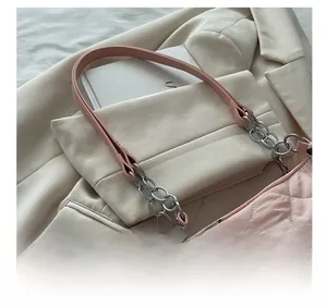 Detail of pink quilted tote bag with chain strap resting on a beige blazer and book