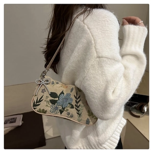 Close-up of floral jacquard crescent bag with silver rhinestone bow and leather strap