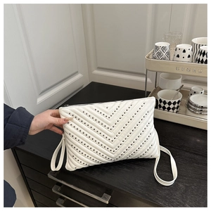 Detail einer weißen gesteppten PU-Ledertasche mit dekorativen Metallnieten