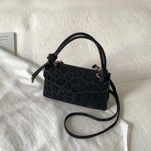 Minimalist black leopard print crossbody bag with knotted handle on white fabric background