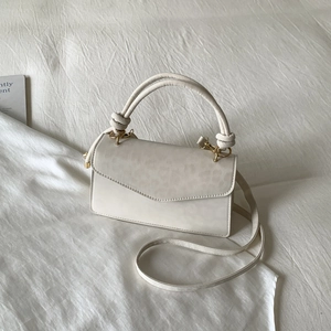 Minimalist beige handbag with leopard print flap and elegant knotted handle design