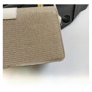 Detail of gold glitter woven fabric texture with white leather trim and metal hardware