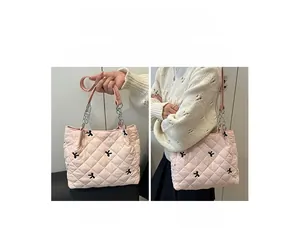 Close-up of pink quilted tote bag with black bow embroidery and silver chain strap
