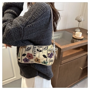 Detail of floral tapestry shoulder bag with woven flower pattern and bead charm