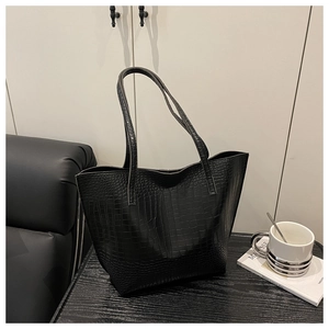 Detailed view of the crocodile pattern texture on a large black faux leather tote bag