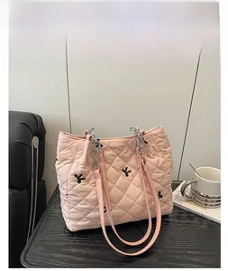 Detailed close-up of pink quilted tote bag with letter K embroidery and chain handles