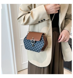 Détail d'un sac bandoulière élégant avec bandoulière chaîne et breloque chat en métal