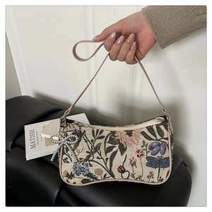 Close-up of floral tapestry baguette bag with pink leather strap and bow charm
