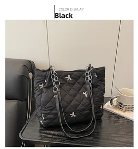 Detail of black quilted tote bag featuring silver bow embroidery and chain straps